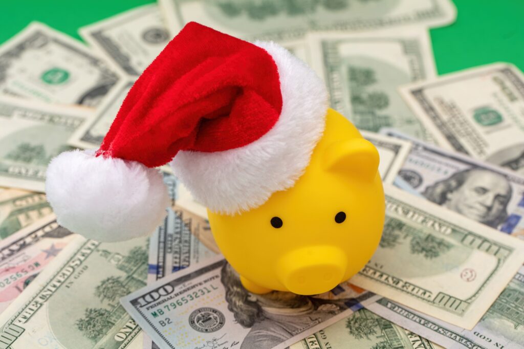 Christmas holiday bonus and expenses. Piggy bank with Santa hat on US dollars money